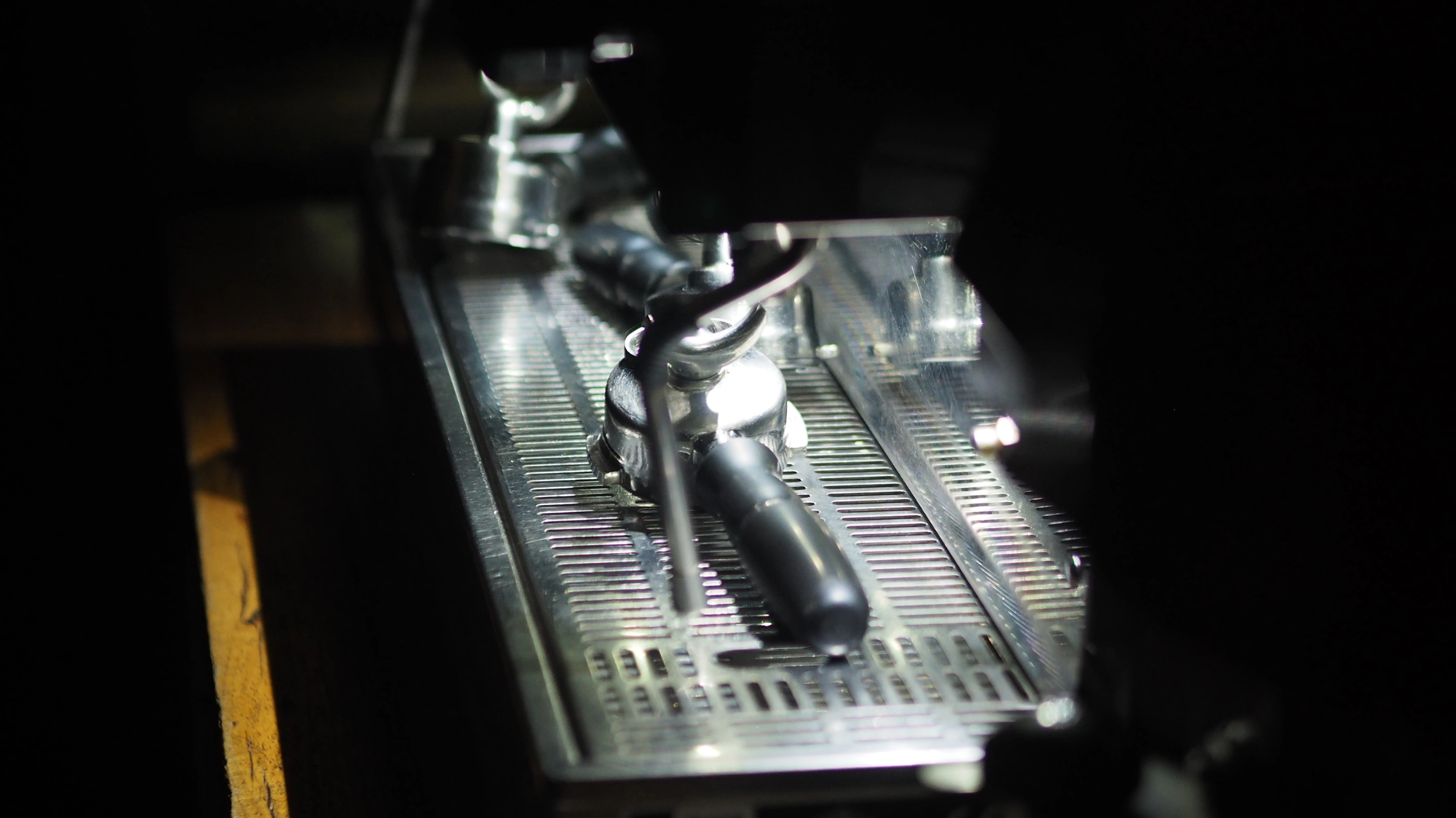 An espresso machine in the dark, with the filter basket placed upside down on the tray.