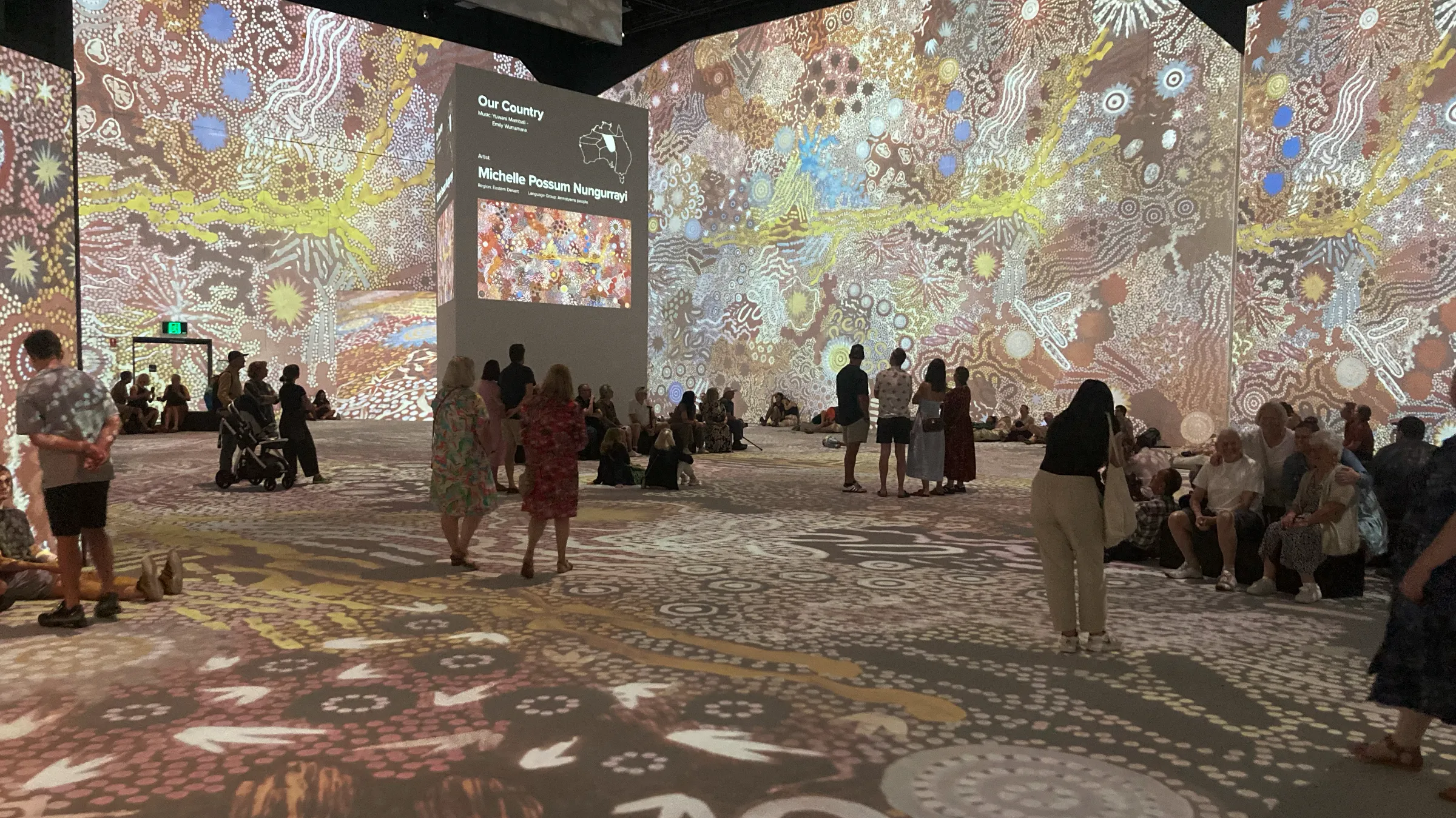 Aboriginal projected on huge screens in a big, dark room.